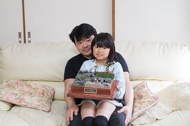 亀田誠さん。手に持っている作品は2014年のモデラーズエキスポで銀賞を受賞した。テーマは家族で行ったスリランカ旅行。
