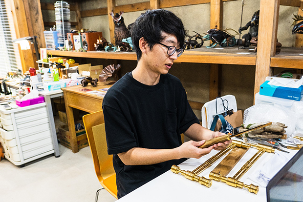 自らの作品を手に取り、制作プロセスを語る木谷氏。現在は大学時代の先輩である金工作家の古田航也氏と共同で工房を構え、制作にいそしんでいる。