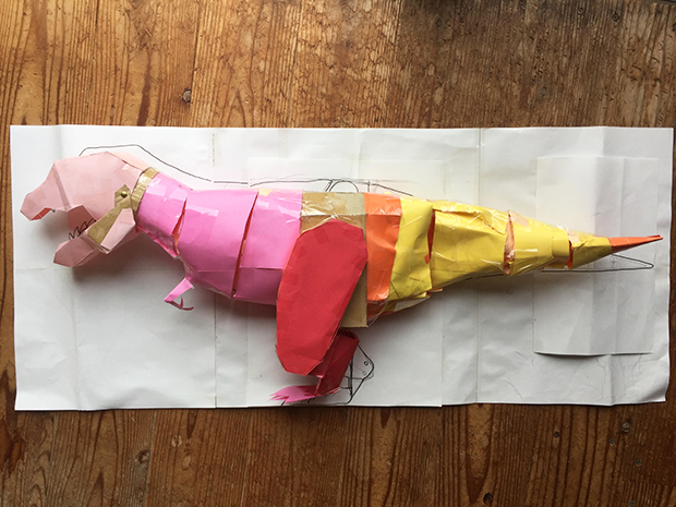 恐竜「シロ」の検討用模型。画用紙とセロテープを駆使して、おおよその形を決める。「この次の模型は部品ごとに作るそばから切って開いて拡大するので、手元には残りません」（ヒゲキタさん）