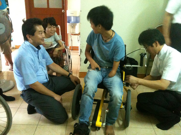 ベトナム・ハノイ市内の障害者支援NPO団体にて。生まれつき腕と脚に障害を持ち立位歩行が困難な男性が、COGYに試乗したあと「こんなに自由に動けたのは初めて」と笑顔を見せた。（写真提供：TESS）