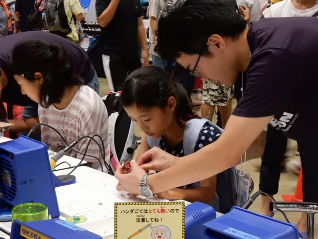 マクニカがスポンサーを務めたMaker Faire Tokyoのはんだ付け体験では、親子で参加する風景も多々見られた。この子供達が大人になる頃には、Makersの環境もさらに変化しているだろう。（写真提供：マクニカ）