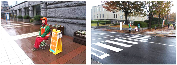 探索エリアにいる4人の探索対象者は、ロボットが識別しやすいように緑色のジャンパーの上にオレンジのベストと帽子を着用し、横に高さ90cmの看板が置かれている（左）。この看板もロボットが識別しやすいように、レーザーを強めに反射するテープが貼ってある。横断歩道は、実際に車が行き交う道路にある（右）。10mほどの距離を20秒以内で渡りきらなければならない。