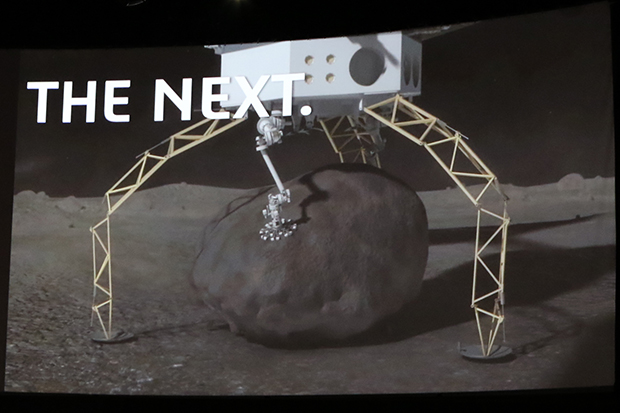 NASAジェット推進研究所が研究中の、小惑星表面の岩塊をつかむロボットアーム。画像で岩に手のひらを広ベル用に接触しているように見える白っぽいもの。