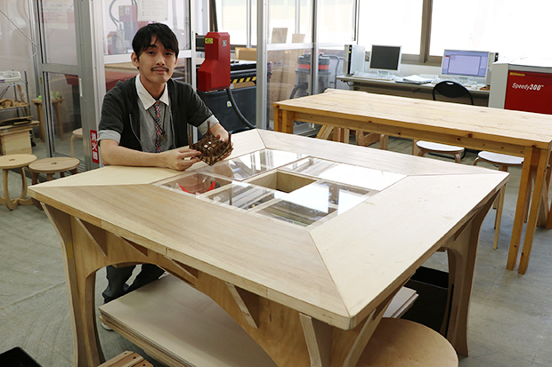 技科大修士2年の加登柊平さん。ラボの技術スタッフとして活躍中。写真のテーブルの製作も行った。