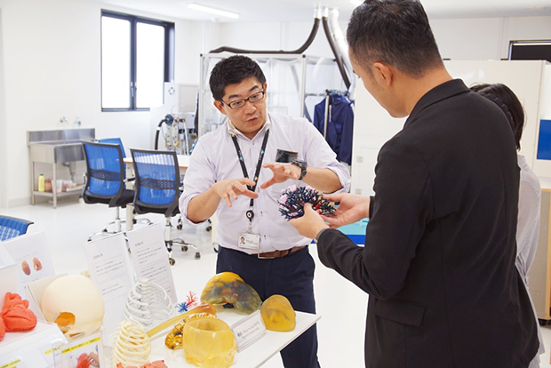 外科手術シミュレーション用の模型の説明をする竹田氏（左）。最初に製造した心臓のモデルは竹田氏自身の心臓をCTスキャンしたものがベースになったという。