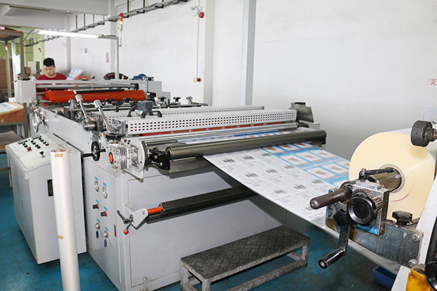 印刷物の表面に光沢と保護のためのPPを貼る機械。工員が一人で機械を操作。